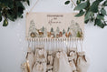Bild in Galerie-Betrachter laden, DIY Adventskalender als Schild, das an der wand hängt mit weihnachtlicher Winterlandschaft und Waldtieren. 24 mit Geschenken befüllte Jutebeutel hängen daran