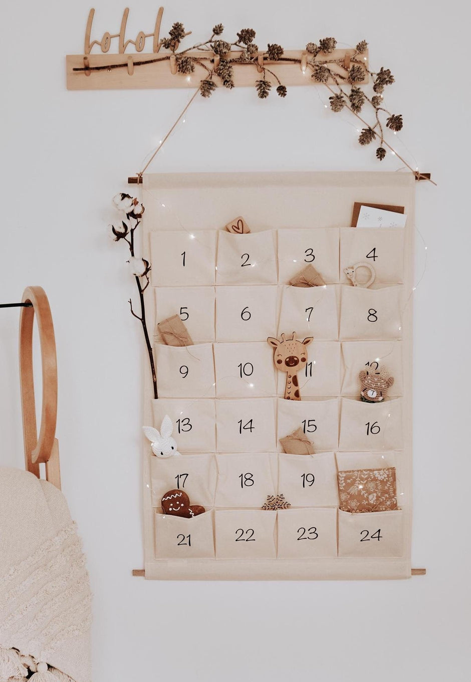 Stoff-Adventskalender mit 24 nummerierten Taschen zum Befüllen, an der Wand aufgehängt, dekoriert mit Baumwollzweig