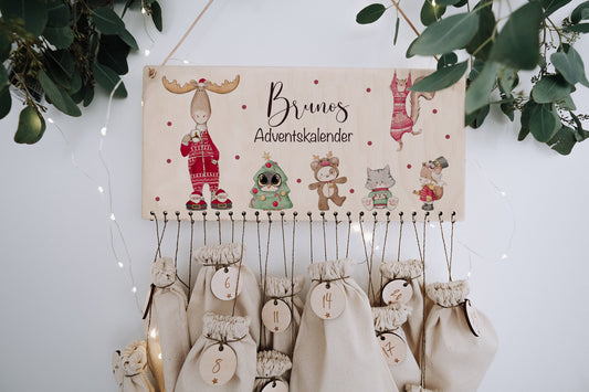 An der Wand hängendes Adventskalenderschild aus Holz mit 24 Adventsbeuteln. Motiv bunte weihnachtlich gekleidete Waldtiere.