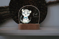 Load image into Gallery viewer, Acrylglas Nachtlicht in dunklem hintergund mit süßem Schneeleopard und personalisierbarer Widmung auf dem Glas und Sockel aus holz
