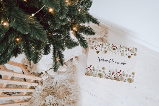 personalisierte Weihnachtskiste mit bunten Tannenbäumen und &quot;Weihnachtswünsche&quot; Schriftzug als Adventskalender für Kinder oder Wunschkiste unter dem Baum neben einem Schlitten weihnachtliche Dekoration